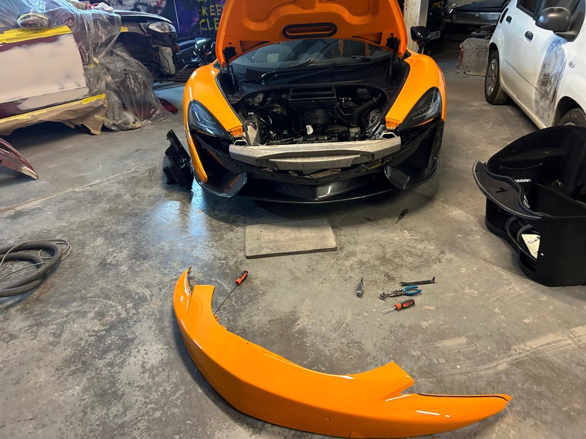 Orange sports car stripped down for bumper and panel repair