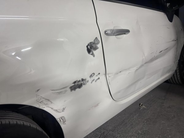 Close-up of dented and scuffed car door before smart repair
