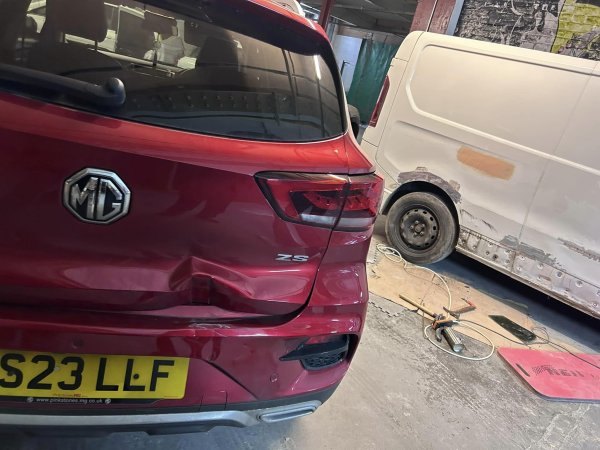 Rear-end accident damage on a red MG awaiting repair